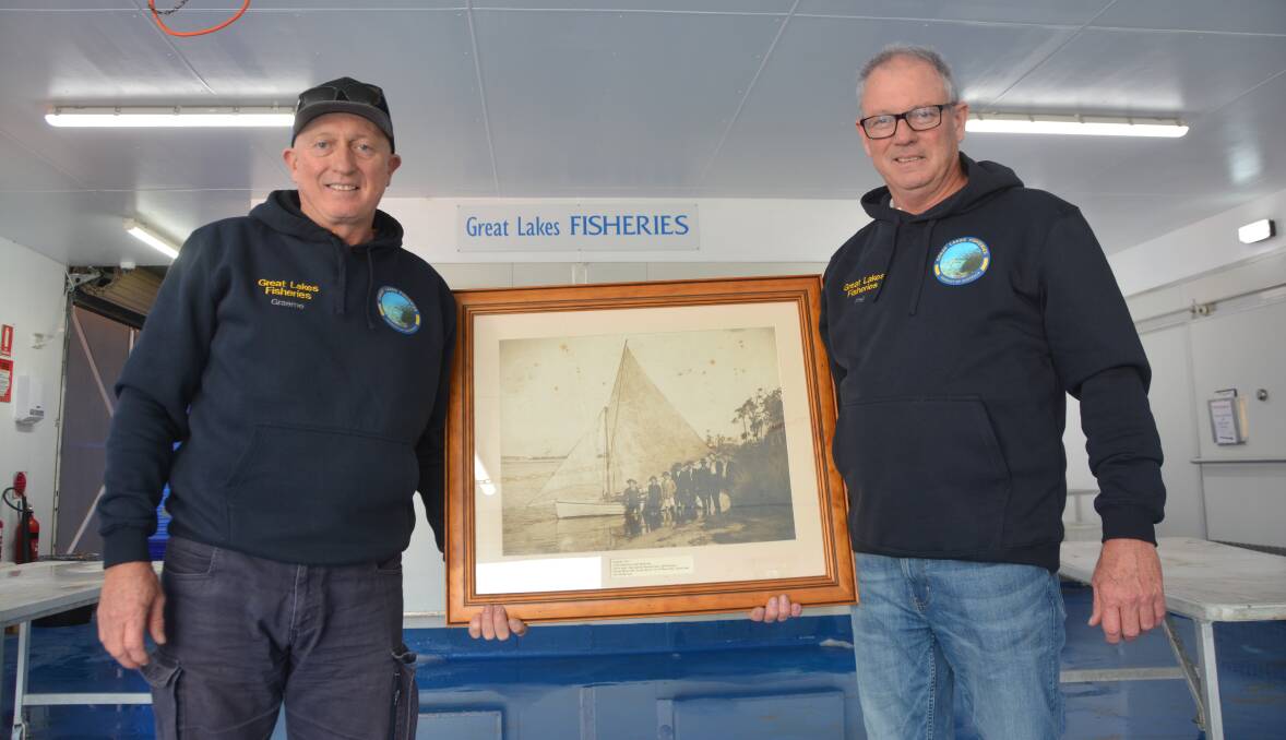 Graeme and Phillip Byrnes with a magnificent large framed photograph of Lake Illawarra and the family boat 'Torment' taken by Fred Combes in approximately 1917.