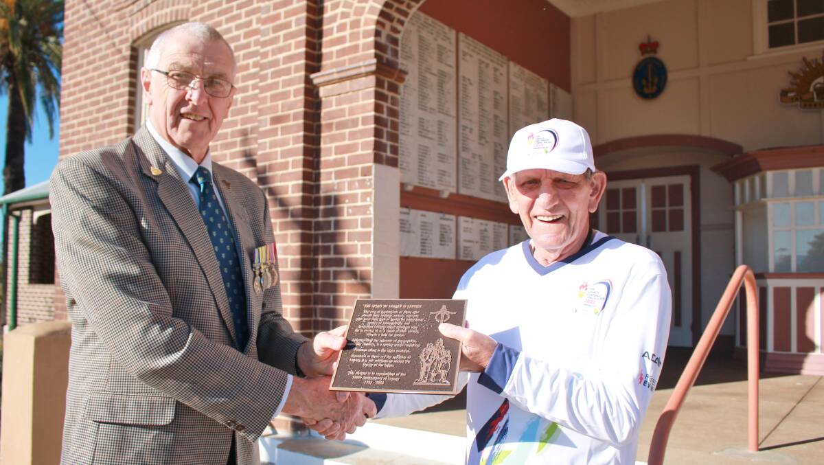 Wingham RSL Sub-branch president Brian Willey accepting a brass plaque commemorating the Legacy centenary torch from Legacy torch bearer, John Rooimans. Picture by Pam Muxlow