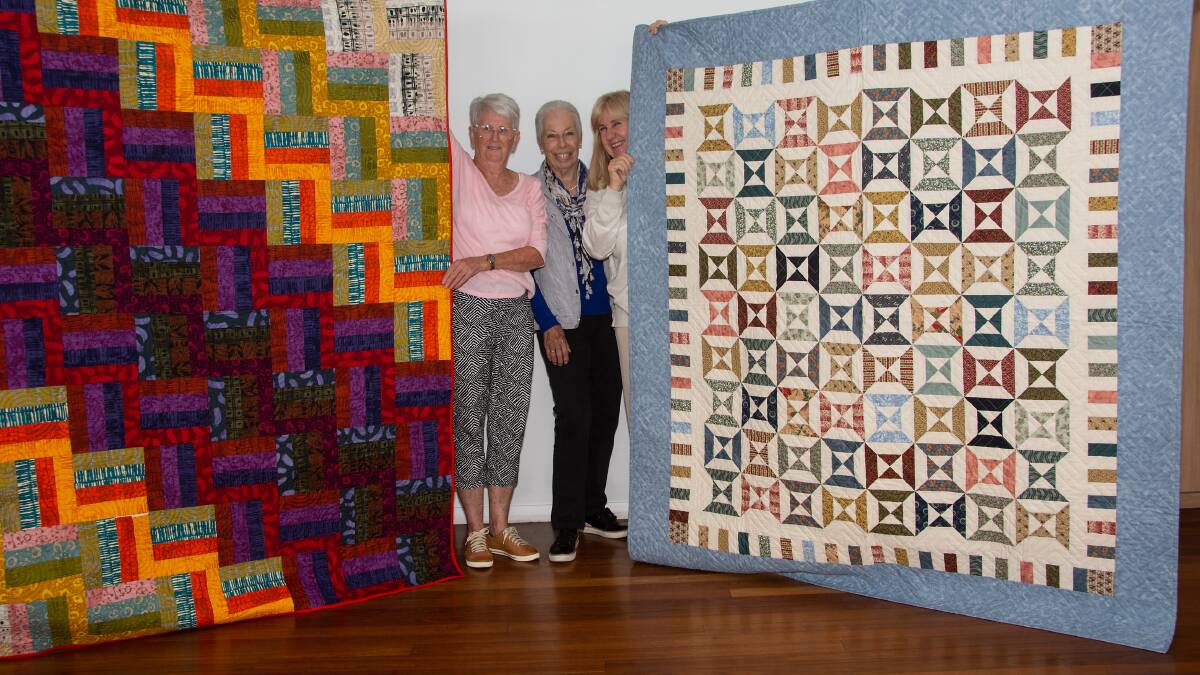 Black Head Beach Quilters members Bronwyn Grant, Heather Rimmer and Cherylee Dee showing off the two raffle prize quilts. Picture supplied